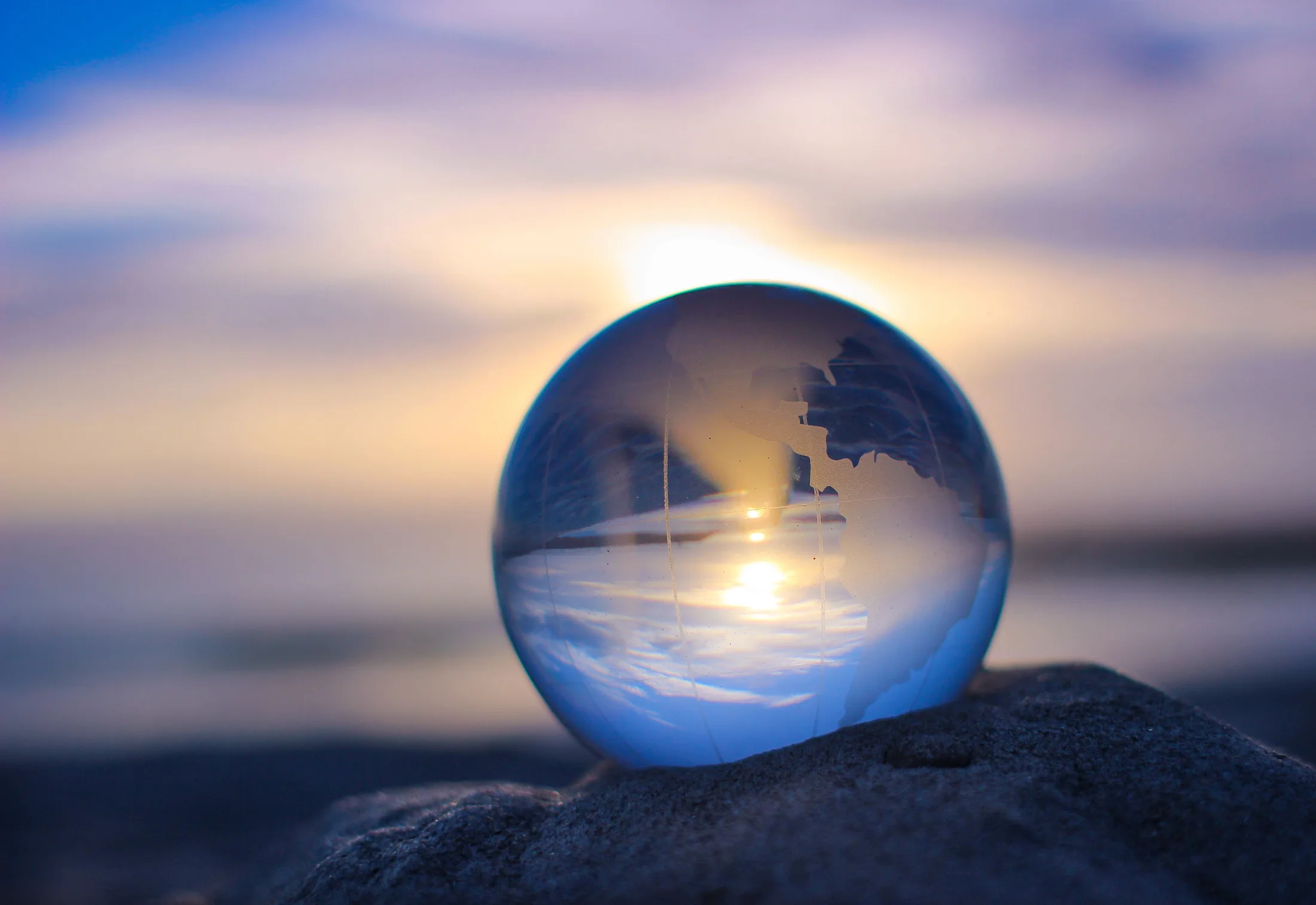 Esfera de cristall amb un globus terraqüi que reflecteix l'aigua i el cel a l'alba